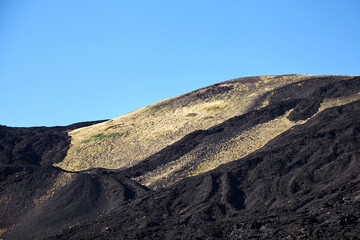 Mount Etna, Sicily, Italy. Slopes of volcano are covered with volcanic ash and frozen lava. Summer mountain landscape on sunny day
