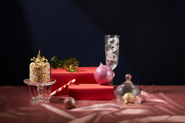 Two red pedestals in rectangle shaped decorated with small and large baubles. Glasses and a candle...