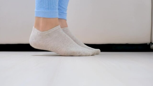 Female legs doing exercises lifting on toes close-up, home workout concept.