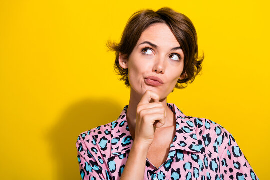 Portrait of pensive minded person hand touch chin look empty space contemplate isolated on yellow color background