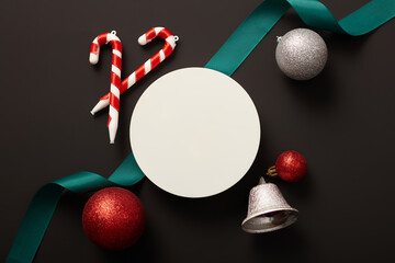 Flat lay of a round podium displayed with sparkling baubles, candy cane and a ribbon. Christmas...