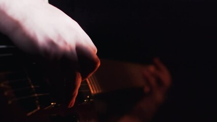 Close-up view of a guitarist playing the melody on a electric guitar during the performance on a stage with multicolor lights. Musician performing a cheerful rock song