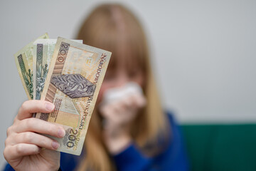 Ofiara oszustwa finansowego trzyma polskie banknoty w dłoniach 