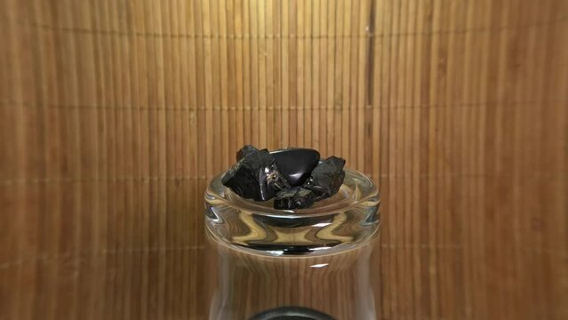 Shungite on a jar against a brown raffia background