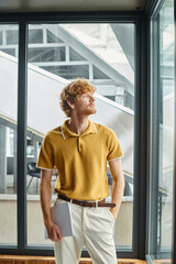 young red haired man in smart casual yellow shirt looking away with window backdrop, coworking