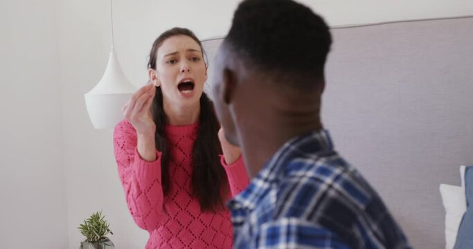 Angry diverse couple arguing and shouting in bedroom at home, slow motion
