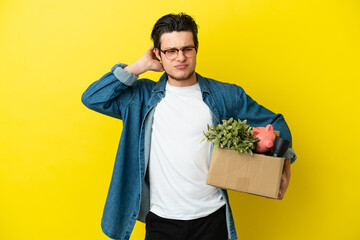 Russian Man making a move while picking up a box full of things isolated on yellow background...