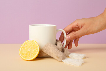 Cup in hand and lemon on pink background