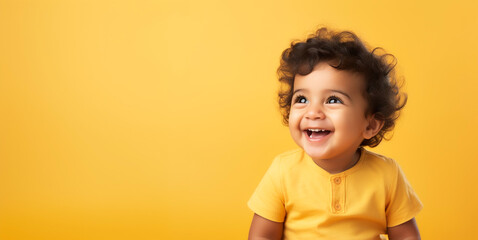 Happy indian baby laughing wearing yellow shirt, isolated on pastel yellow background - 656933301