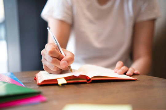Businesswoman writing in diary with pen