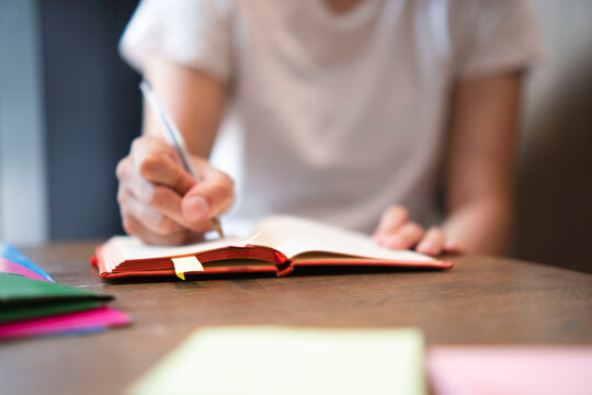 Businesswoman writing in diary on table