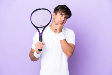 Handsome young tennis player man isolated on ocher background having doubts