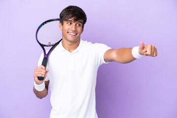 Handsome young tennis player man isolated on ocher background giving a thumbs up gesture