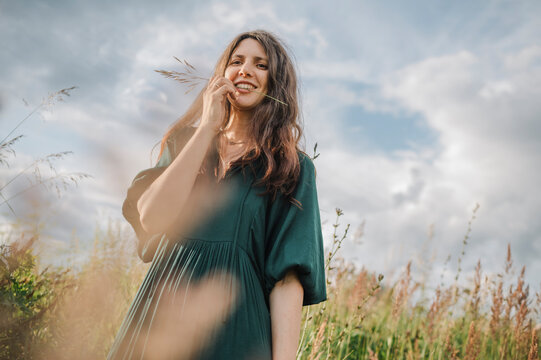 Happy woman biting twig under cloudy sky