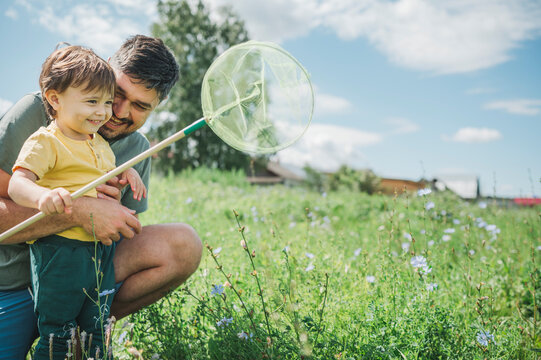 Happy father catching butterfly with son in garden
