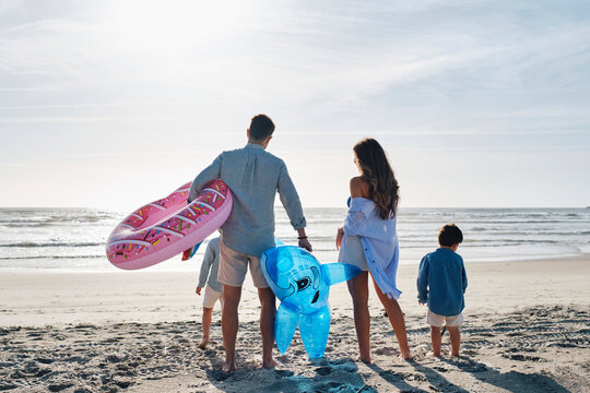 Family with inflatable swim ring and toy shark standing together at beach