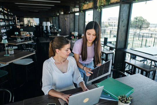 Two young women working together on sustainable resources project at coworking space