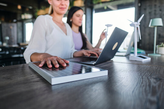 Hand of young woman testing solar panel while working at coworking space