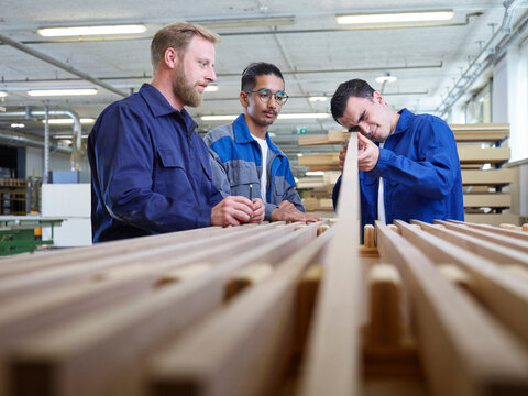 Trainee checking quality of wooden plank in factory