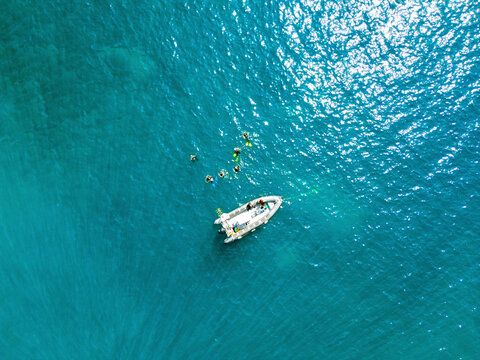 Drone view of group of divers swimming near floating motorboat