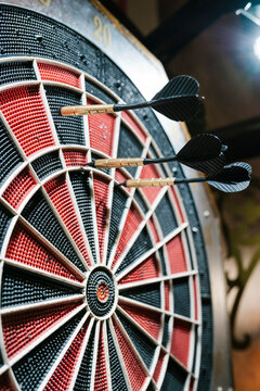 Three black darts hitting the dartboard in bar