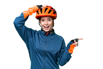 Young cyclist woman over isolated chroma key background surprised and pointing finger to the side