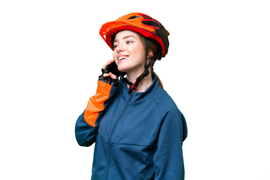 Young cyclist woman over isolated chroma key background keeping a conversation with the mobile phone
