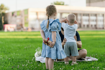 little kids presenting his dad a gift on a father's day, happy family on a grass field