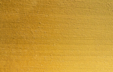 Gold wall texture background. Yellow shiny gold foil on concrete wall surface, vibrant golden luxury wallpaper