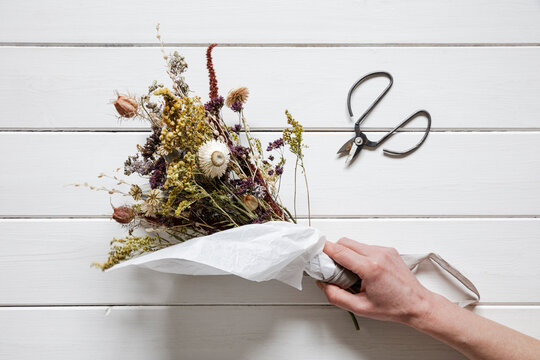 Hand of woman picking up bouquet of dried flowers