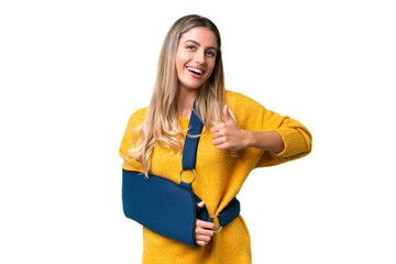 Young Uruguayan woman with broken arm and wearing a sling over isolated background giving a thumbs...