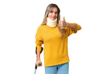 Young Uruguayan woman wearing neck brace and crutches over isolated background with thumbs up...