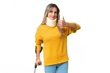 Young Uruguayan woman wearing neck brace and crutches over isolated background with thumbs up because something good has happened