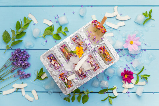Homemade lemonade ice pops with herbs, edible flowers and coconut flakes