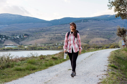 Young tourist walking on footpath in front of mountain