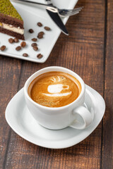 Patterned cappuccino coffee in a white porcelain cup on a wooden table