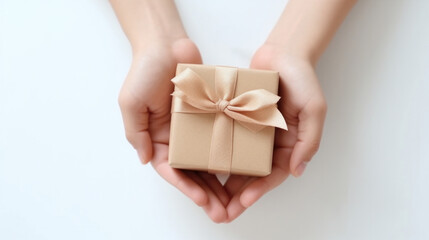 Woman hands holding small gift box isolated on a white background, top view