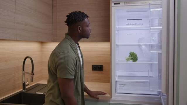 Hungry Black Man Opening Empty Fridge. Frustrated African American Male Wants To Eat, But There Is No Food At Home.