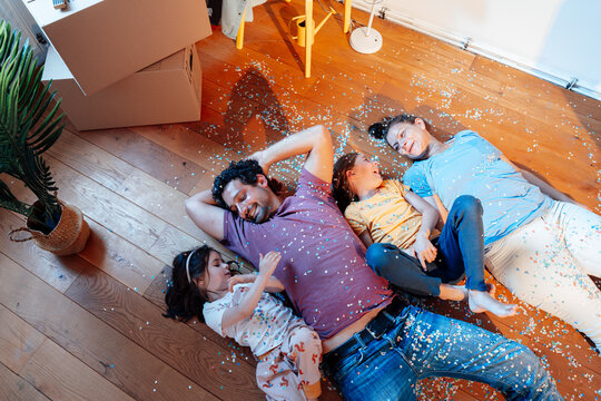 Happy family together lying with confetti on floor at home
