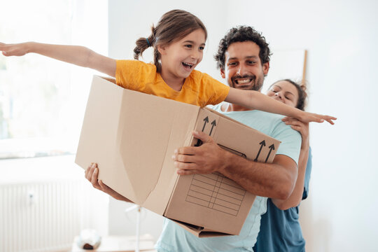 Happy father and mother with playful daughter sitting in box 