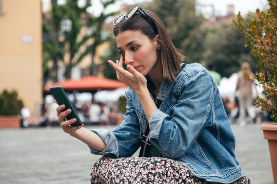 Woman examining eye looking at smart phone