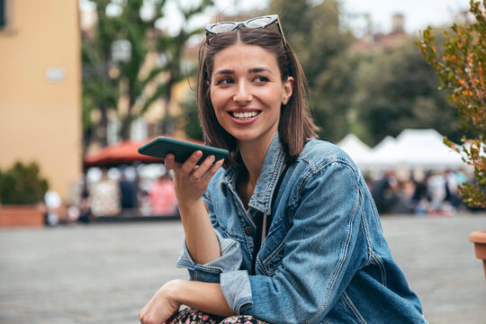 Smiling woman sending voicemail through smart phone