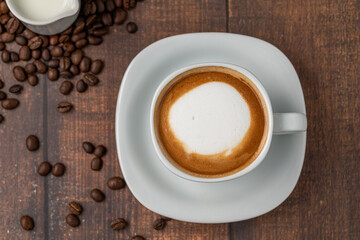 Relaxing latte coffee in white porcelain cup on wooden table