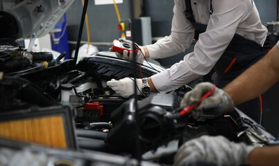 Car repair technicians use voltage multimeter to work in auto repair shops. Diagnostics of car...