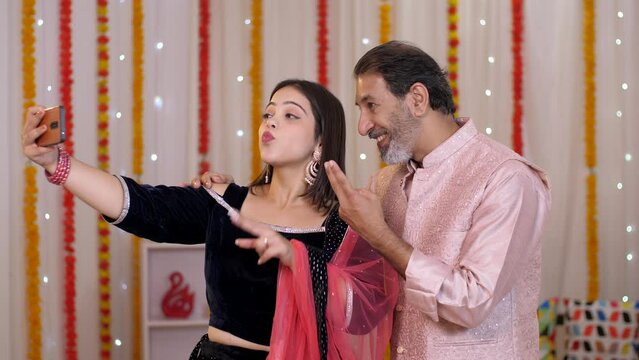 A young girl and her father clicking a selfie together on a mobile - Diwali celebration  father-daughter bonding  happy family  festive vibes. Father-daughter wearing ethnic clothes spend time toge...