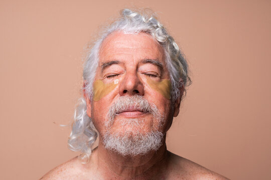 Senior man with eye patch against beige background