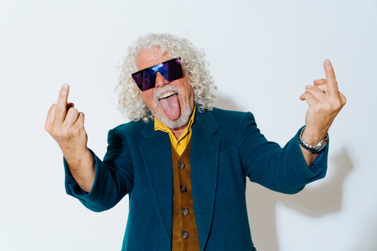 Cheerful man sticking out tongue and showing obscene gesture