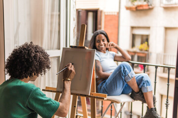 Boyfriend painting on canvas with girlfriend posing at home