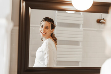 Smiling bride looking in mirror at home