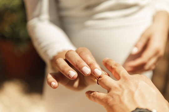 Hand of bride putting wedding ring on groom's finger